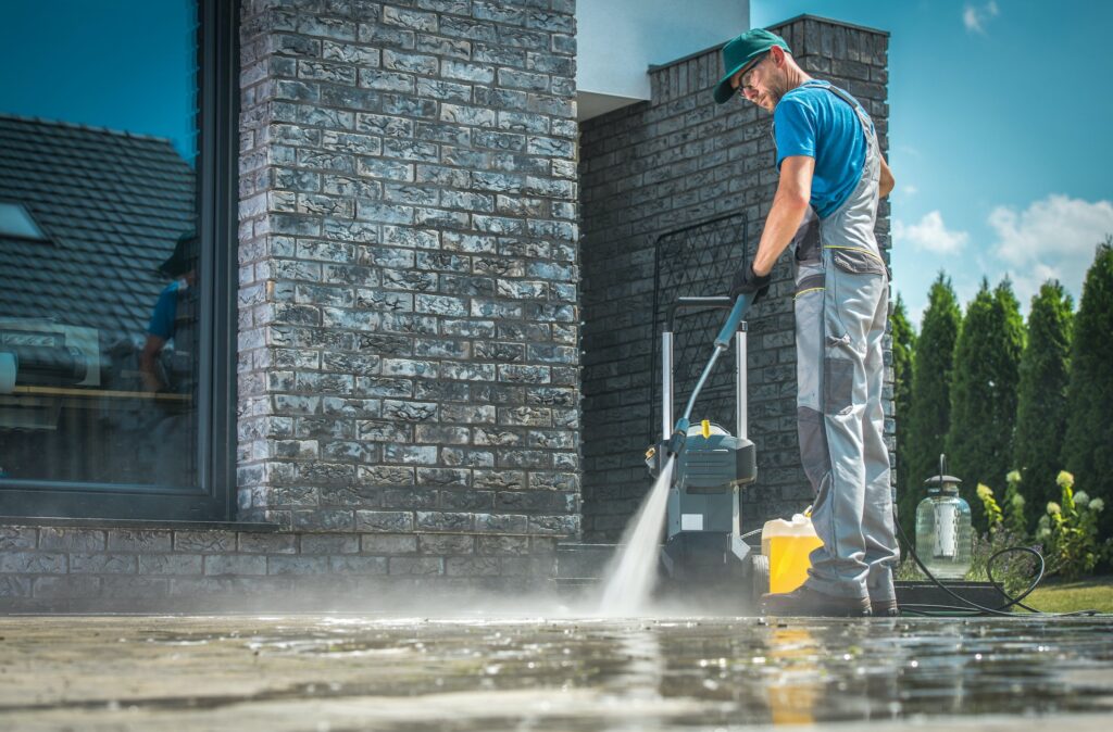 Worker pressuring washing residential home sidewalk